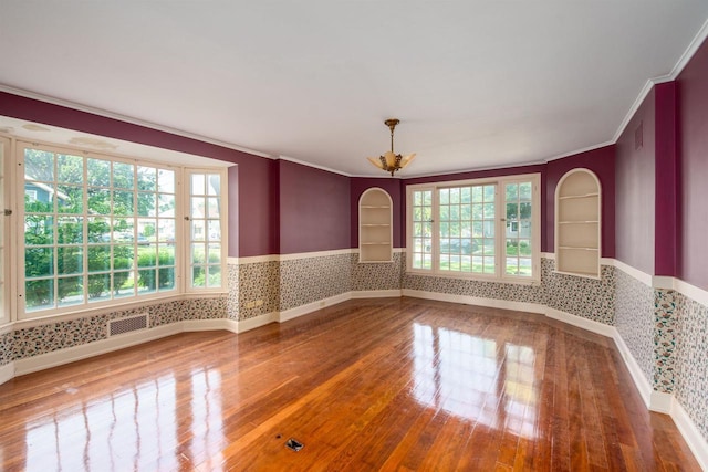 645 Wisconsin St, Oshkosh, WI 54901 - unfurnished room with wallpapered walls, a wainscoted wall, hardwood / wood-style floors, ornamental molding, and built in shelves