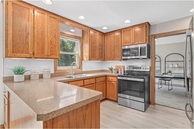 3203 Canterbury Cir, Saint Paul, MN 55125 - kitchen with stainless steel appliances, a peninsula, light wood-style flooring, brown cabinetry, and backsplash