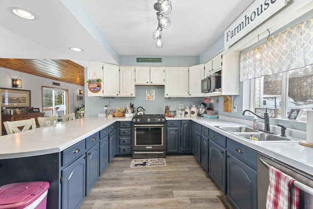 W6815 N Walworth Rd, Walworth, WI 53184 - kitchen featuring stainless steel appliances, blue cabinets, a peninsula, recessed lighting, and white cabinetry