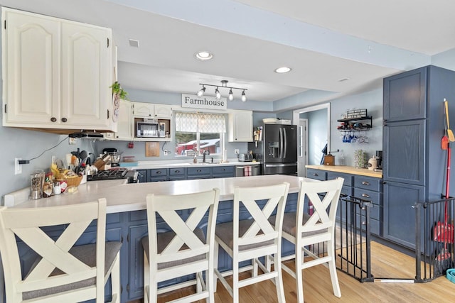 W6815 N Walworth Rd, Walworth, WI 53184 - kitchen featuring appliances with stainless steel finishes, light countertops, a peninsula, light wood-style flooring, and recessed lighting