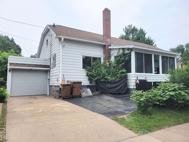 1425 Rogers St, Stevens Point, WI 54481 - view of property exterior featuring a chimney, a sunroom, concrete driveway, and a garage