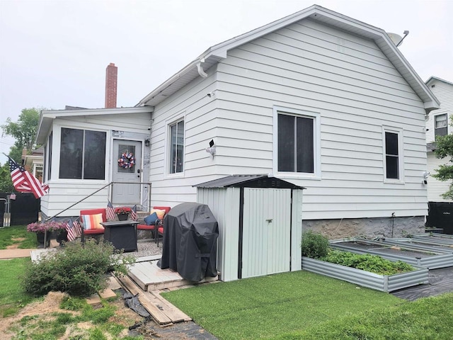 1425 Rogers St, Stevens Point, WI 54481 - back of property featuring a lawn, a garden, a chimney, and a shed
