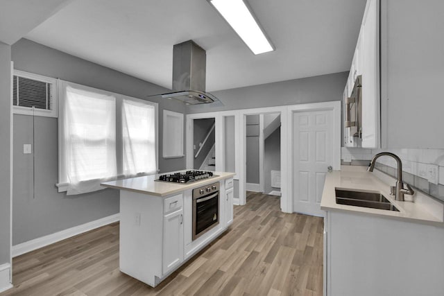 2863 N 38th St, Milwaukee, WI 53210 - kitchen with appliances with stainless steel finishes, island range hood, white cabinetry, light countertops, and light wood-type flooring