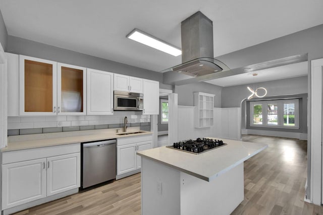 2863 N 38th St, Milwaukee, WI 53210 - kitchen with appliances with stainless steel finishes, island range hood, light wood-style floors, white cabinets, and light countertops