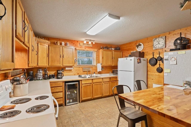 7454 State Highway 186, Arpin, WI 54410 - kitchen featuring white appliances, beverage cooler, wood walls, a textured ceiling, and brown cabinets