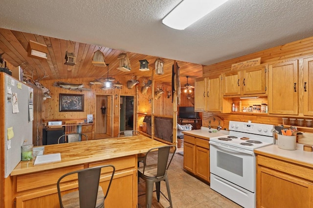 7454 State Highway 186, Arpin, WI 54410 - kitchen with white electric range, wooden walls, a breakfast bar, a textured ceiling, and a peninsula