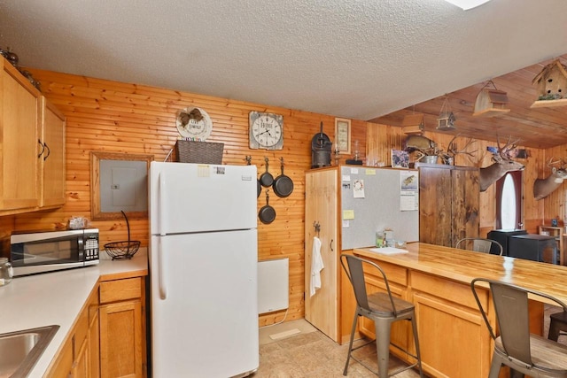 7454 State Highway 186, Arpin, WI 54410 - kitchen with freestanding refrigerator, stainless steel microwave, wood walls, electric panel, and a textured ceiling