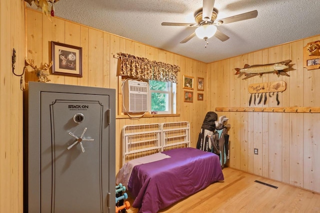 7454 State Highway 186, Arpin, WI 54410 - bedroom with a textured ceiling, wood walls, wood finished floors, a wall mounted AC, and a ceiling fan