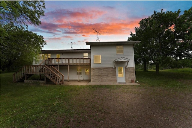 1231 135th St, Amery, WI 54005 - back of property featuring stairs, stone siding, a deck, a patio, and a yard