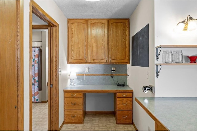 1231 135th St, Amery, WI 54005 - kitchen featuring brown cabinetry, light countertops, a desk, a textured ceiling, and light floors