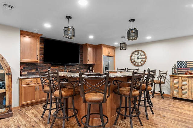 4140 N Prairie Rose Ln, Appleton, WI 54913 - indoor wet bar with stainless steel refrigerator with ice dispenser, decorative backsplash, light wood finished floors, recessed lighting, and hanging light fixtures