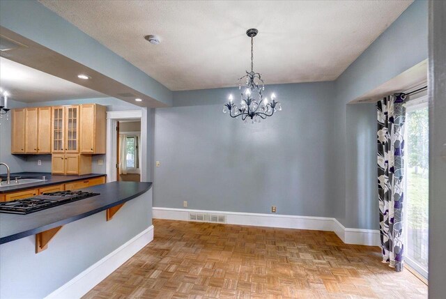 31 Elm St, Fort Atkinson, WI 53538 - kitchen with black gas stovetop, dark countertops, light brown cabinetry, a chandelier, and a kitchen bar