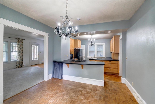 31 Elm St, Fort Atkinson, WI 53538 - kitchen with freestanding refrigerator, a chandelier, dark countertops, a peninsula, and decorative light fixtures