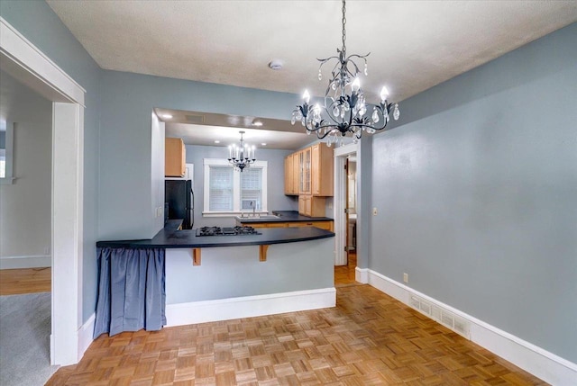 31 Elm St, Fort Atkinson, WI 53538 - kitchen featuring a chandelier, dark countertops, freestanding refrigerator, a kitchen bar, and a peninsula