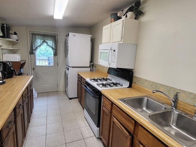 9317 N Arrowhead Shores Rd, Edgerton, WI 53534 - kitchen featuring gas range, white microwave, estacked washer and dryer, light tile patterned floors, and brown cabinetry