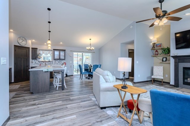 8810 Hinner Springs Dr, Weston, WI 54476 - living room featuring vaulted ceiling, light wood finished floors, a glass covered fireplace, a chandelier, and a ceiling fan