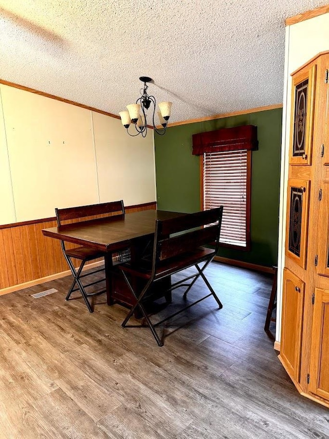 691 Valley Trl, Nekoosa, WI 54457 - dining area featuring crown molding, a textured ceiling, a chandelier, wood finished floors, and wainscoting