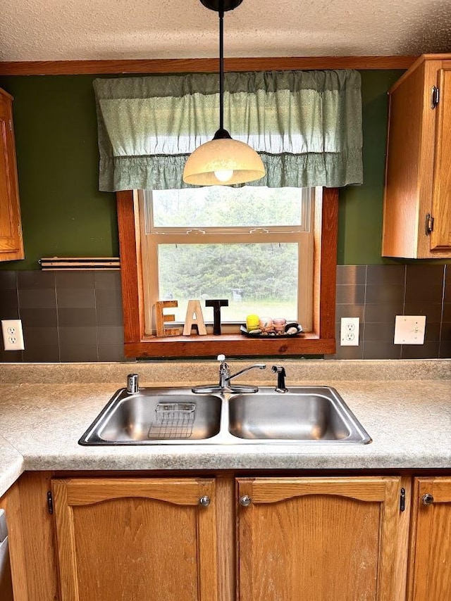 691 Valley Trl, Nekoosa, WI 54457 - kitchen with light countertops, tasteful backsplash, a textured ceiling, brown cabinets, and decorative light fixtures