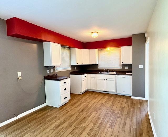 1710 N 25th St, Sheboygan, WI 53081 - kitchen featuring light wood-type flooring, dishwasher, white cabinetry, and dark countertops
