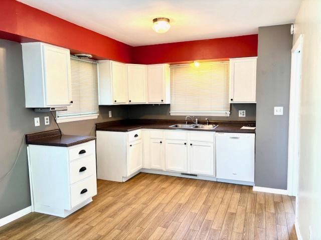 1710 N 25th St, Sheboygan, WI 53081 - kitchen with dishwasher, light wood finished floors, dark countertops, and white cabinetry