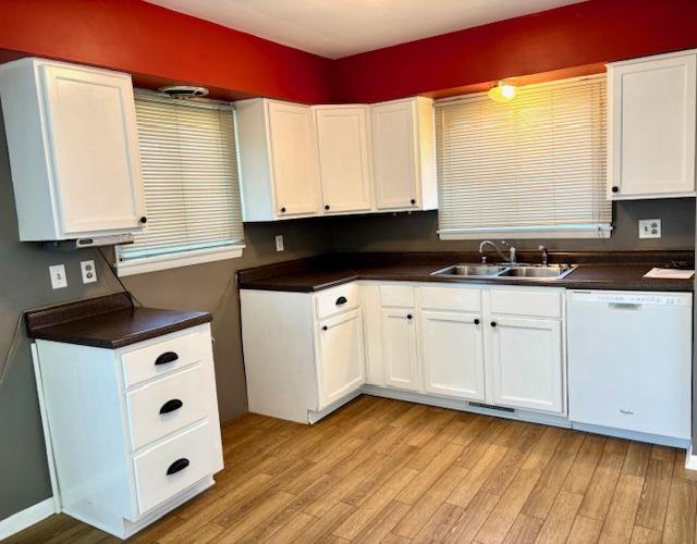 1710 N 25th St, Sheboygan, WI 53081 - kitchen with white dishwasher, light wood-style floors, dark countertops, and white cabinets