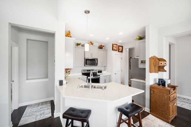 2701 Esker Dr, West Bend, WI 53095 - kitchen featuring appliances with stainless steel finishes, a breakfast bar, a peninsula, dark wood-style floors, and recessed lighting