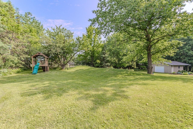 1340 Deer Brook Ct, Wausau, WI 54401 - view of green lawn with a playground, a garage, and view of wooded area