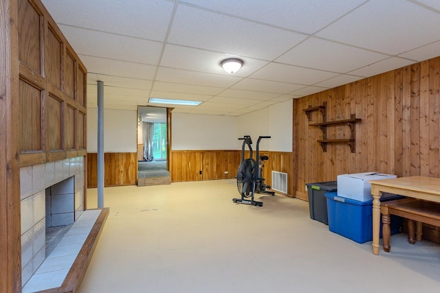 1340 Deer Brook Ct, Wausau, WI 54401 - exercise room featuring wood walls, a tiled fireplace, a paneled ceiling, and wainscoting