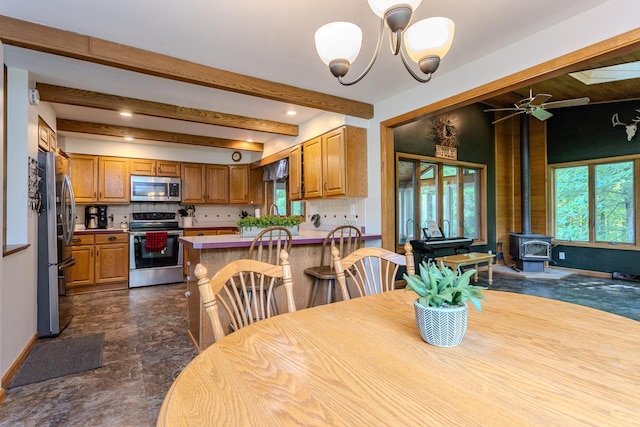 1340 Deer Brook Ct, Wausau, WI 54401 - dining area featuring a wood stove, a chandelier, beam ceiling, ceiling fan, and recessed lighting