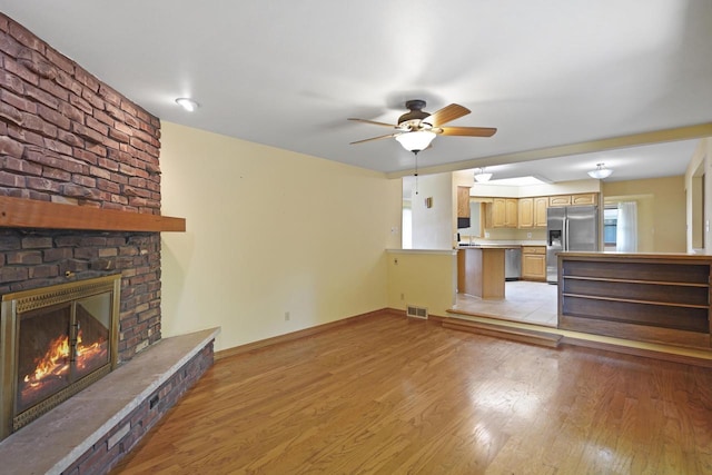 8074 48th Ave, Kenosha, WI 53142 - unfurnished living room featuring ceiling fan, light wood-type flooring, a fireplace, and healthy amount of natural light