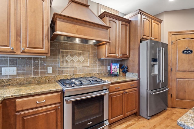 6507 Willow Ct, Waterford, WI 53185 - kitchen with appliances with stainless steel finishes, wall chimney exhaust hood, light wood finished floors, brown cabinetry, and recessed lighting
