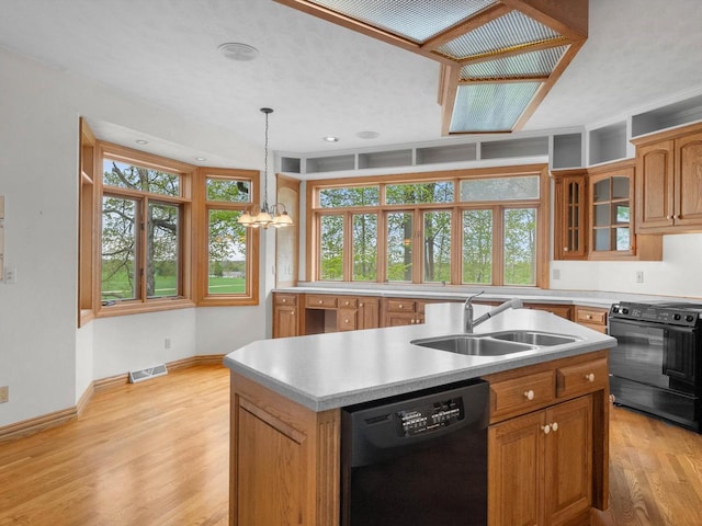 4228 County Hwy W, Valders, WI 54245 - kitchen featuring dishwashing machine, black electric range, a center island with sink, light wood finished floors, and light countertops