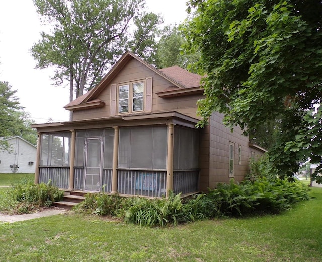 208 S Walker St, Wautoma, WI 54982 - view of front of house featuring a sunroom, a front yard, and a shingled roof
