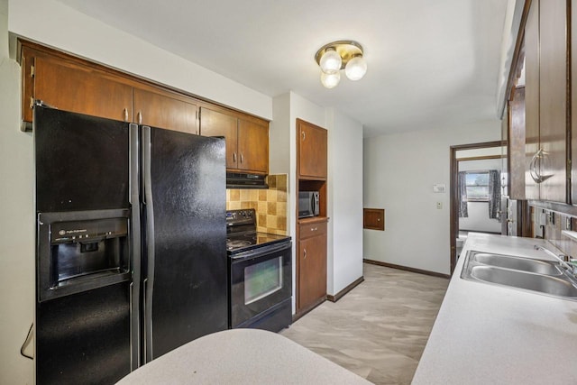 3838 N 78th St, Milwaukee, WI 53222 - kitchen featuring black appliances, range hood, decorative backsplash, light countertops, and brown cabinets