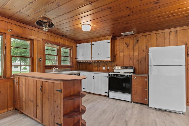8950 Pine Ln, Fremont, WI 54940 - kitchen with freestanding refrigerator, stove, wood ceiling, white cabinetry, and wooden walls