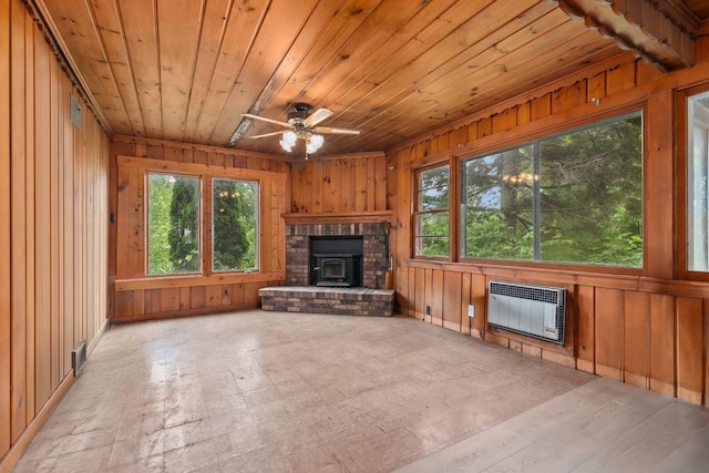 8950 Pine Ln, Fremont, WI 54940 - unfurnished living room with plenty of natural light, wood walls, wood ceiling, a wood stove, and a ceiling fan