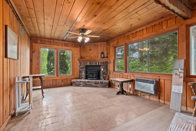 8950 Pine Ln, Fremont, WI 54940 - unfurnished living room featuring wood walls, plenty of natural light, wooden ceiling, a wood stove, and a ceiling fan