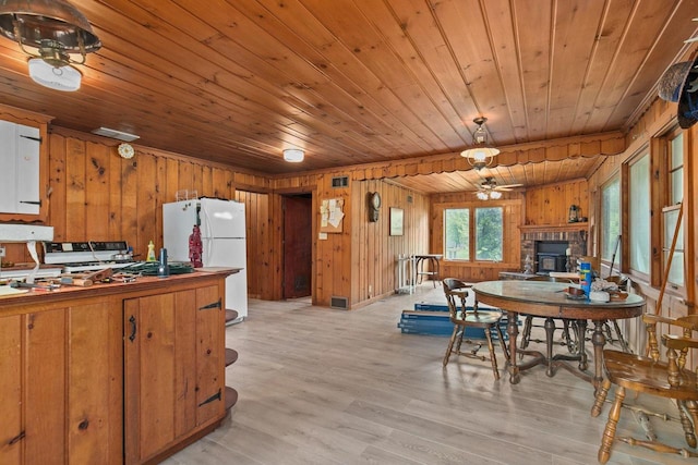 8950 Pine Ln, Fremont, WI 54940 - dining space featuring wood ceiling, wood walls, a stone fireplace, light wood-style floors, and a ceiling fan