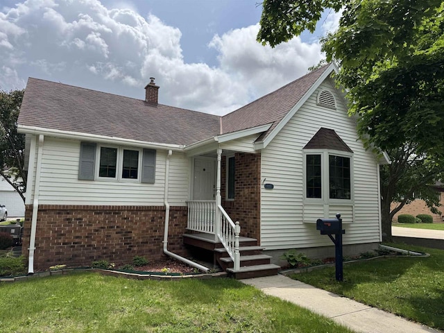 600 Forest Ave, Fond Du Lac, WI 54935 - view of front of house featuring a chimney, a front lawn, brick siding, and roof with shingles