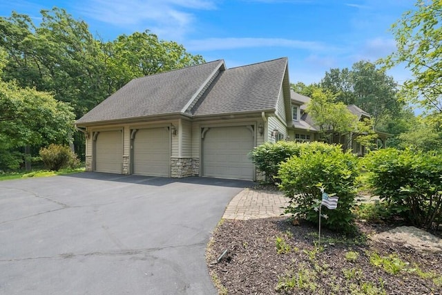 N1760 W Valley Park Rd, Lake Geneva, WI 53147 - view of side of home featuring a garage, asphalt driveway, stone siding, and a shingled roof