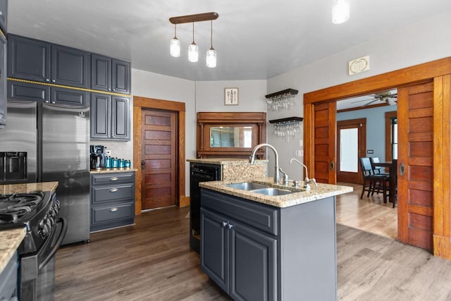 628 Broad St, Menasha, WI 54952 - kitchen with black range with gas stovetop, wood finished floors, a ceiling fan, an island with sink, and light stone countertops