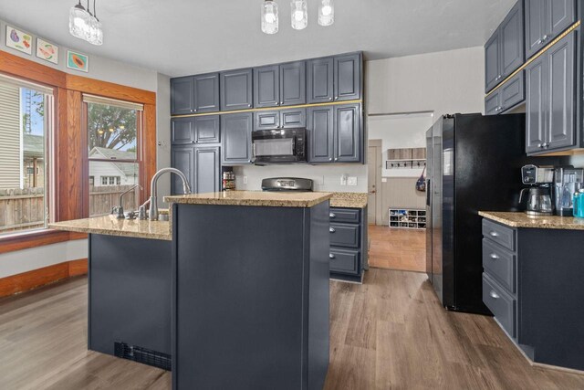 628 Broad St, Menasha, WI 54952 - kitchen featuring black microwave, wood finished floors, a center island with sink, and stainless steel fridge with ice dispenser