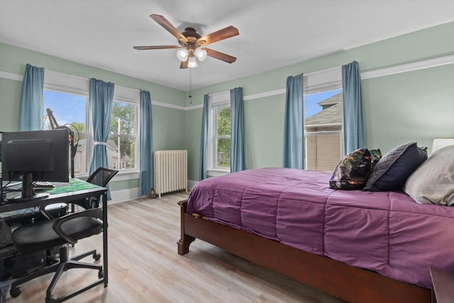 628 Broad St, Menasha, WI 54952 - bedroom featuring radiator heating unit, an office area, light wood-style floors, and a ceiling fan