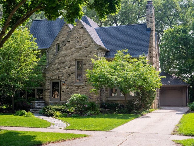 2544 N 91st St, Wauwatosa, WI 53226 - tudor-style house featuring a chimney, a front yard, driveway, roof with shingles, and stone siding