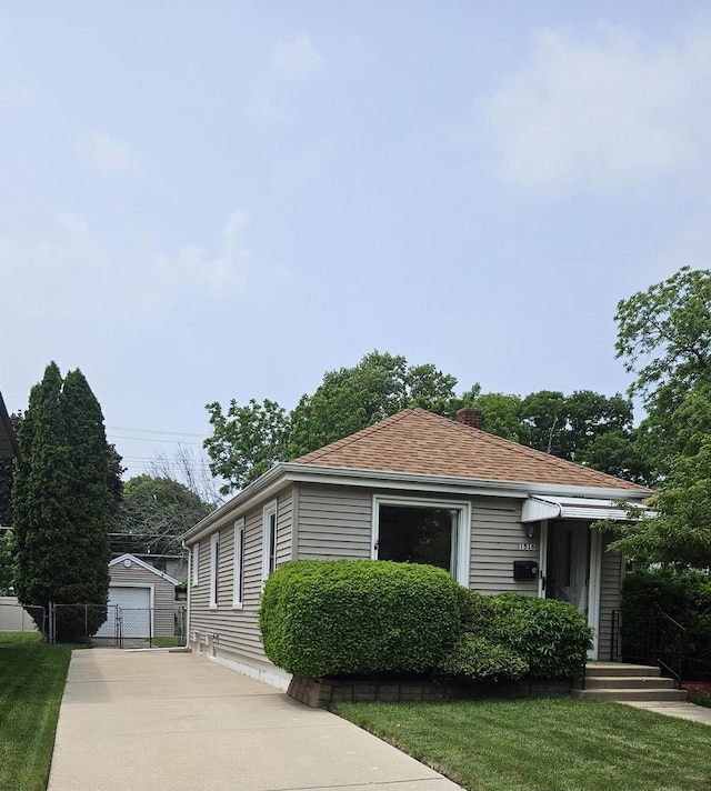 1518 Lathrop Ave, Racine, WI 53405 - view of front of house featuring an outdoor structure, concrete driveway, a garage, a chimney, and roof with shingles