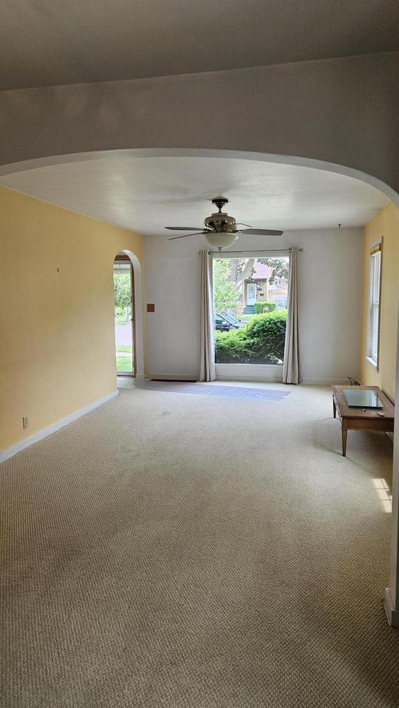 1518 Lathrop Ave, Racine, WI 53405 - empty room featuring arched walkways, carpet flooring, a ceiling fan, and healthy amount of natural light