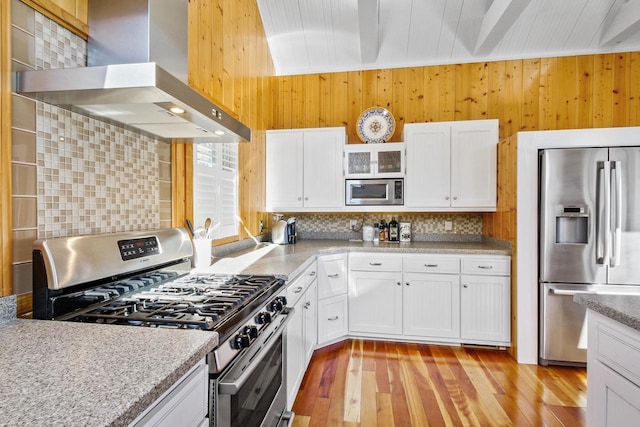 W5374 Westshore Dr, Elkhorn, WI 53121 - kitchen with appliances with stainless steel finishes, wall chimney range hood, wood walls, light wood finished floors, and tasteful backsplash