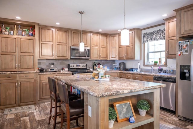 W5671 8th St, Necedah, WI 54646 - kitchen featuring stainless steel appliances, open shelves, a center island, light stone counters, and wood finished floors