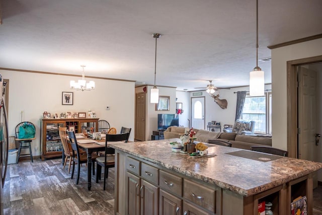 W5671 8th St, Necedah, WI 54646 - kitchen with a chandelier, dark wood finished floors, a ceiling fan, a kitchen island, and ornamental molding