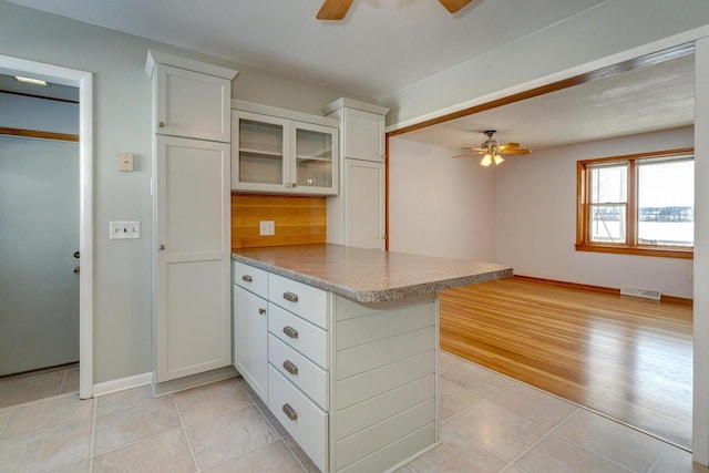 6592 Whalen Rd, Verona, WI 53593 - kitchen with ceiling fan, a peninsula, white cabinets, glass insert cabinets, and light tile patterned floors